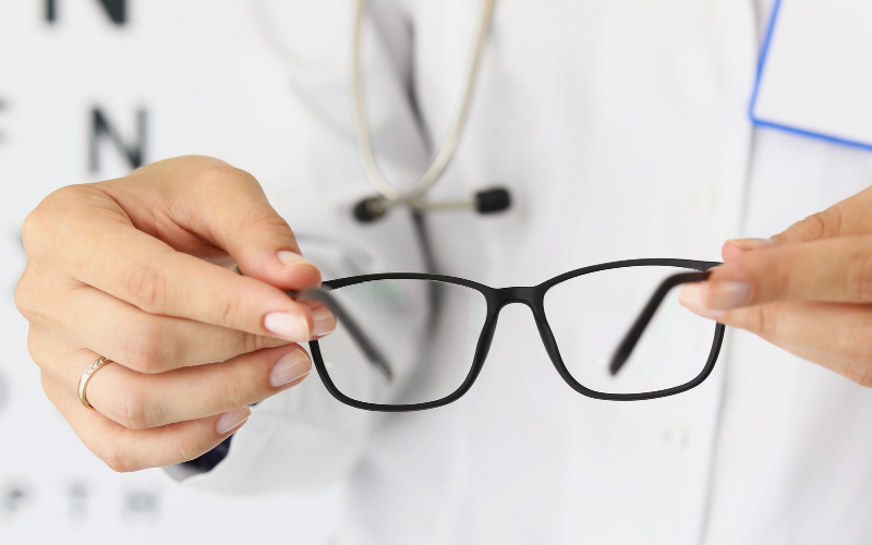 doctora sosteniendo gafas nuevas en óptica