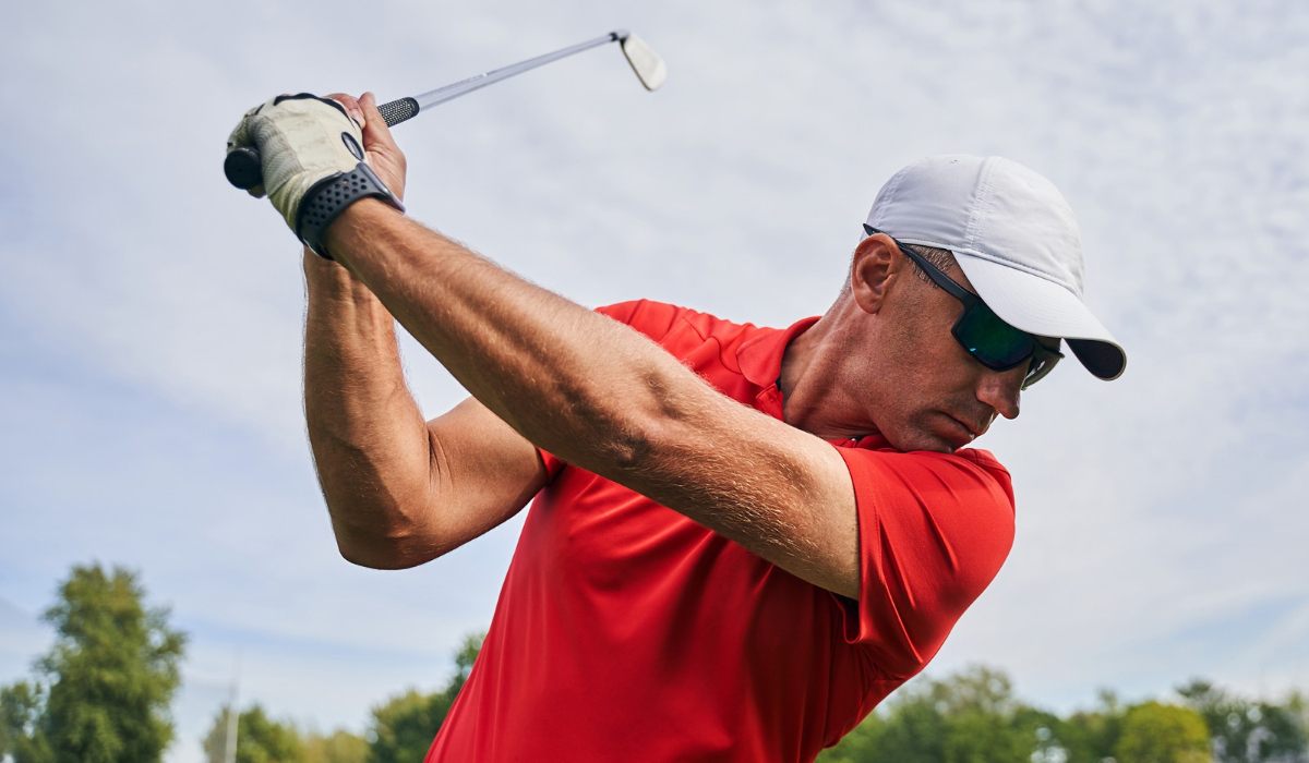 hombre práctica golf con lentes de sol