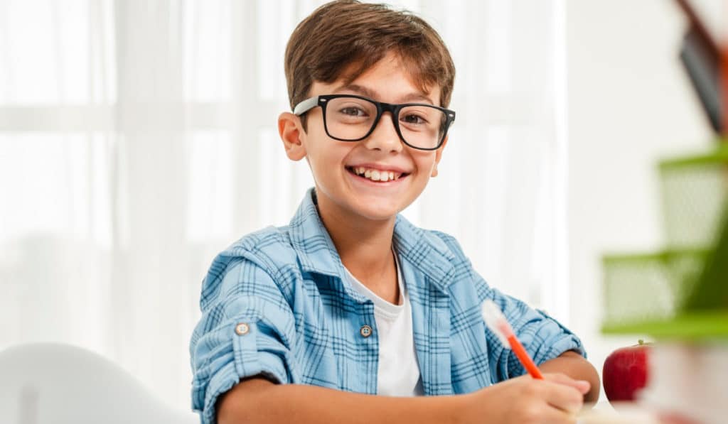 niño estudiando sonrrie con lentes