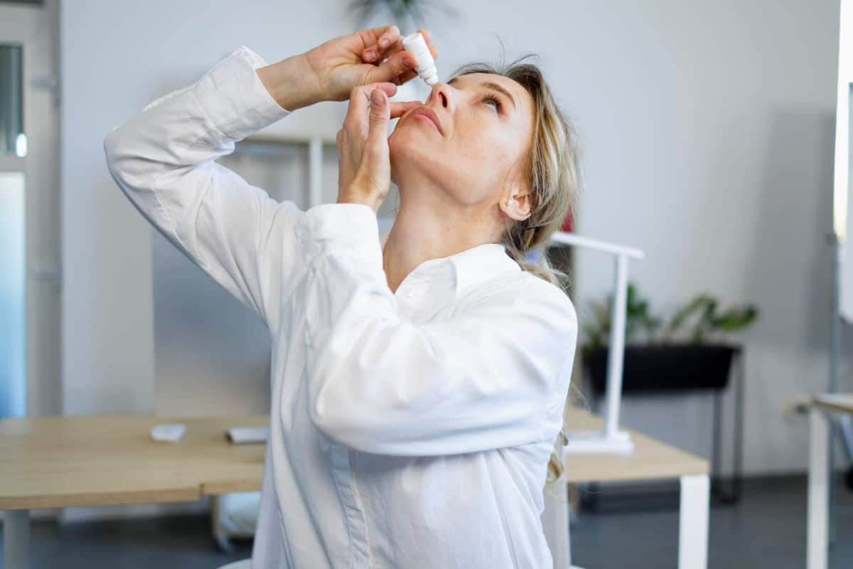 mujer atractiva se aplica gotas en los ojos