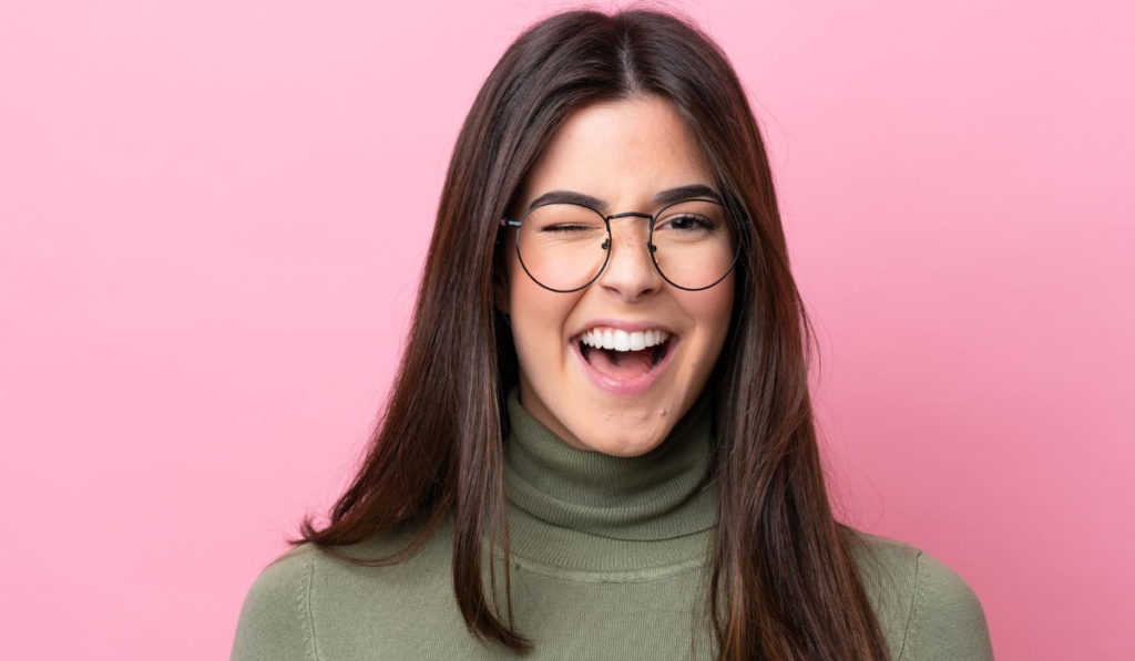 mujer joven pica el ojo con gafas